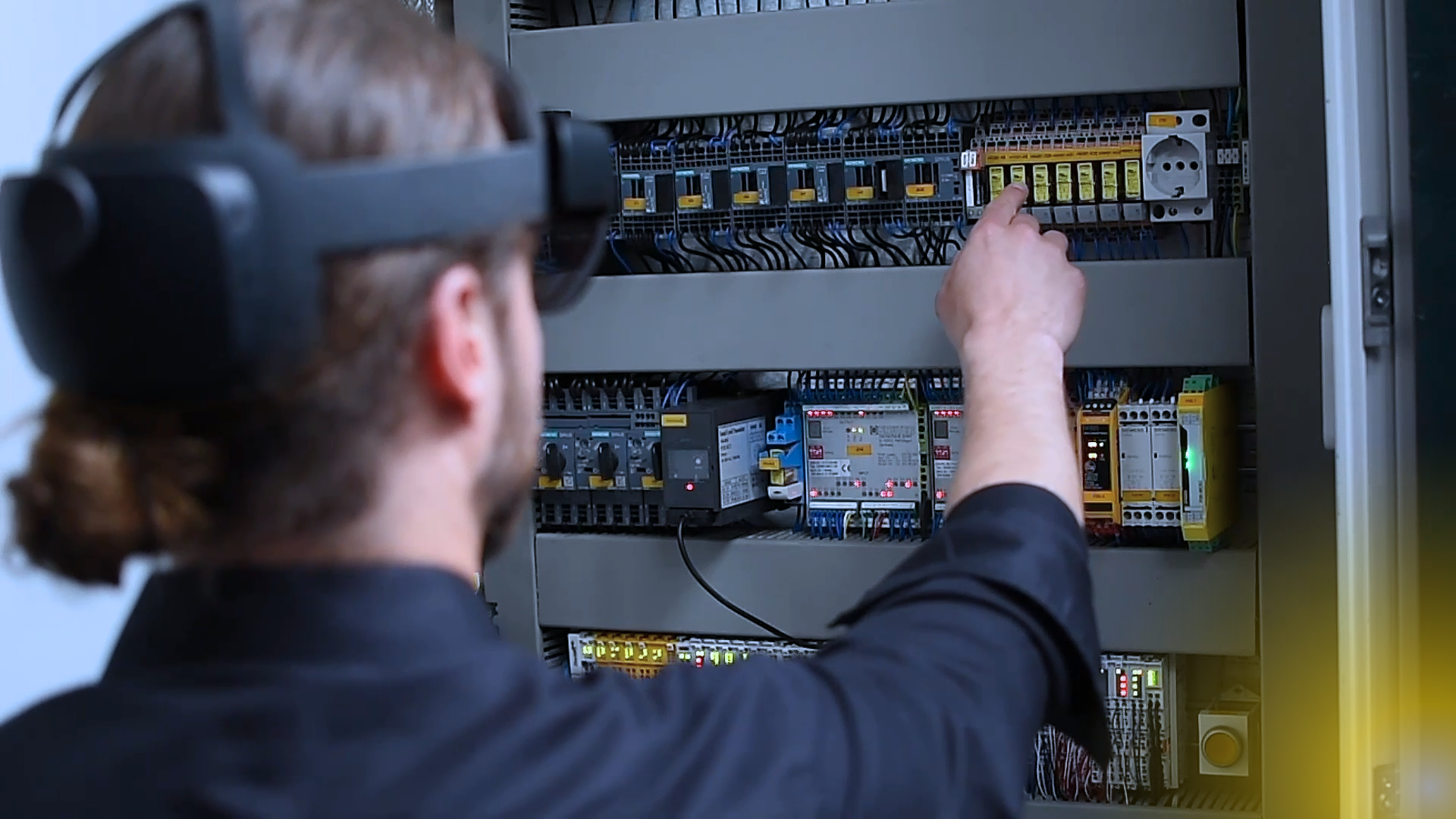 Ein Mann trägt eine Virtual-Reality-Brille und arbeitet an einem Bedienfeld.